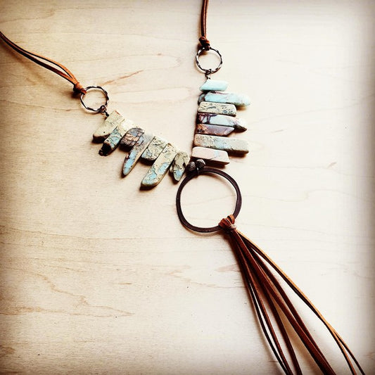 Necklace with stone pendant and tassel on a wooden surface