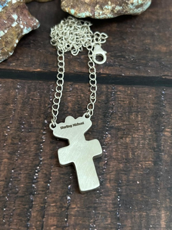 Silver cross necklace on a wooden surface
